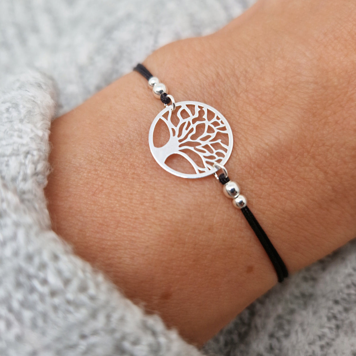 Zartes Makramee-Armband aus schwarzem Band mit 925-Silber-Lebensbaum und Silber-Perlen am Handgelenk des Models in Nahaufnahme