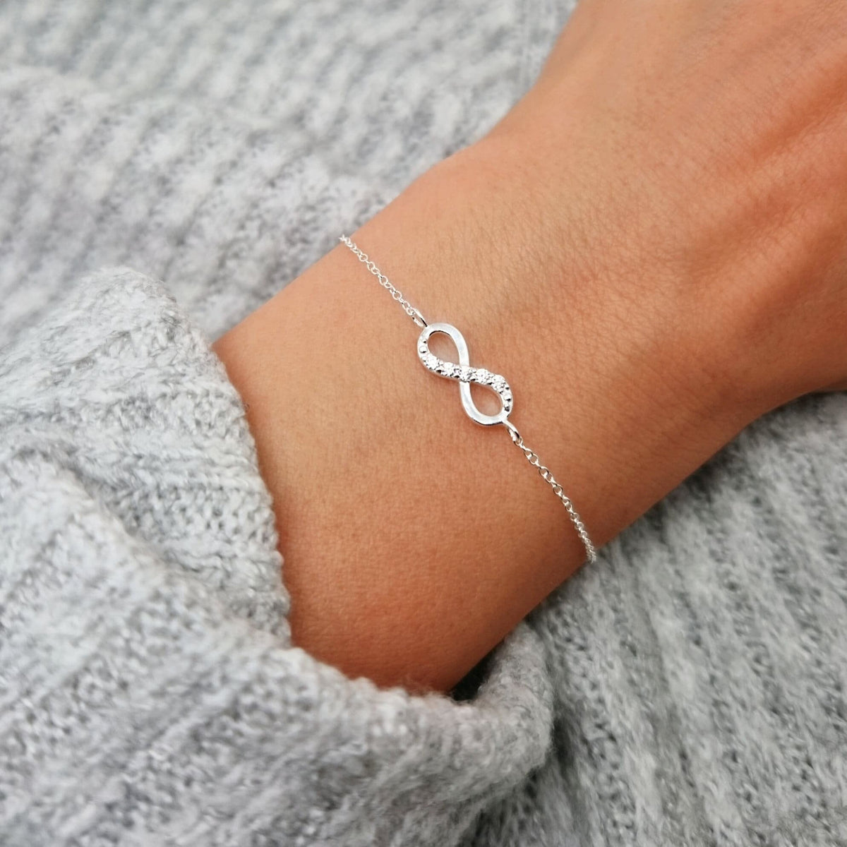 Silbernes filigranes Armband mit Unendlichkeits-Zeichen in Silber mit Zirkonia Kristallen aufcder oberen Linie des Unendlichkeirsszeichens am Handgelenk des Models.