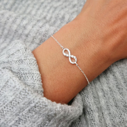 Silbernes filigranes Armband mit Unendlichkeits-Zeichen in Silber mit Zirkonia Kristallen aufcder oberen Linie des Unendlichkeirsszeichens am Handgelenk des Models.