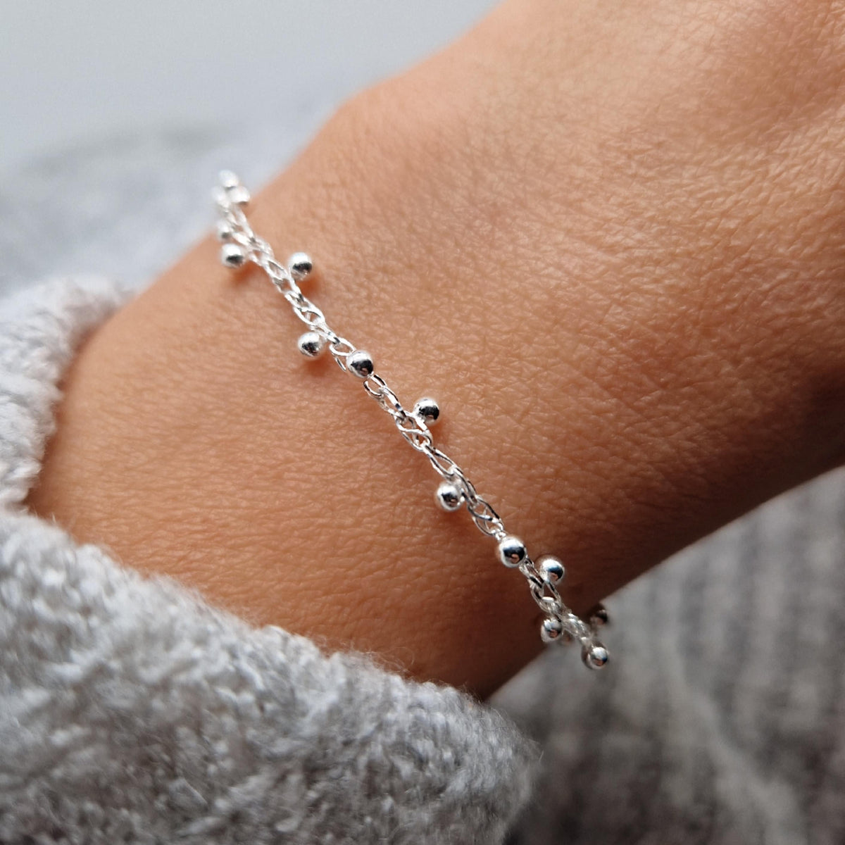 Filigrane gewebte Armkette mit Kugeln aus Silber am Handgelenk des Models. Die Kugeln sind jeweils seitlich versetzt und umlaufend angeordnet.