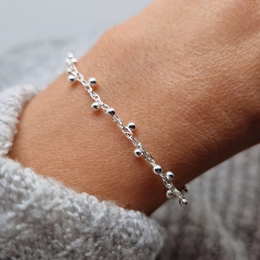 Filigrane gewebte Armkette mit Kugeln aus Silber am Handgelenk des Models. Die Kugeln sind jeweils seitlich versetzt und umlaufend angeordnet.