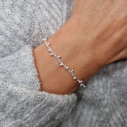 Filigrane gewebte Armkette mit Kugeln aus Silber am Handgelenk des Models. Die Kugeln sind seitlich versetzt und umlaufend angeordnet.