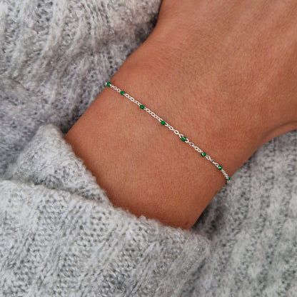 Zartes 925 Silber-Armband aus einer Ankerkette mit grünen Perlen aus Emaille am Handgelenk des Models in Nahaufnahme