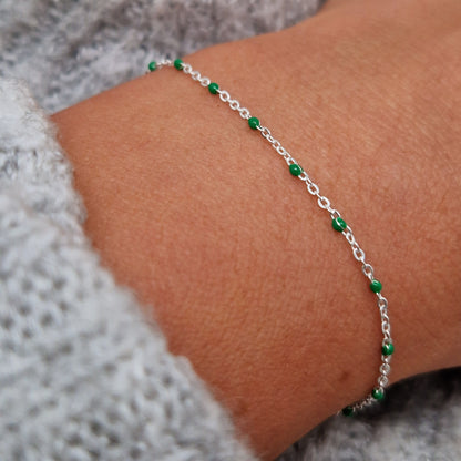 Zartes 925 Silber-Armband aus einer Ankerkette mit grünen Perlen aus Emaille am Handgelenk des Models in seitlicher Nahaufnahme