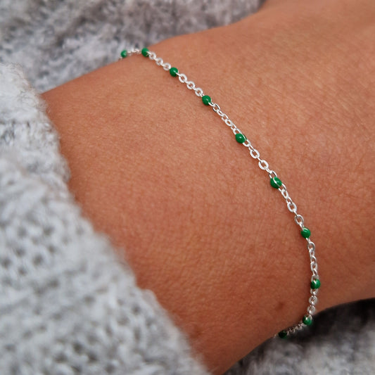 Zartes 925 Silber-Armband aus einer Ankerkette mit grünen Perlen aus Emaille am Handgelenk des Models in seitlicher Nahaufnahme