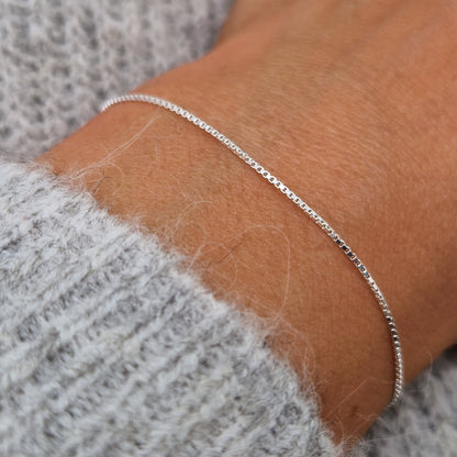 Sehr feines schmales zartes Silberarmband im eckigen Venezianer Stil am Handgelenk des Models in seitlicher Nahaufnahme
