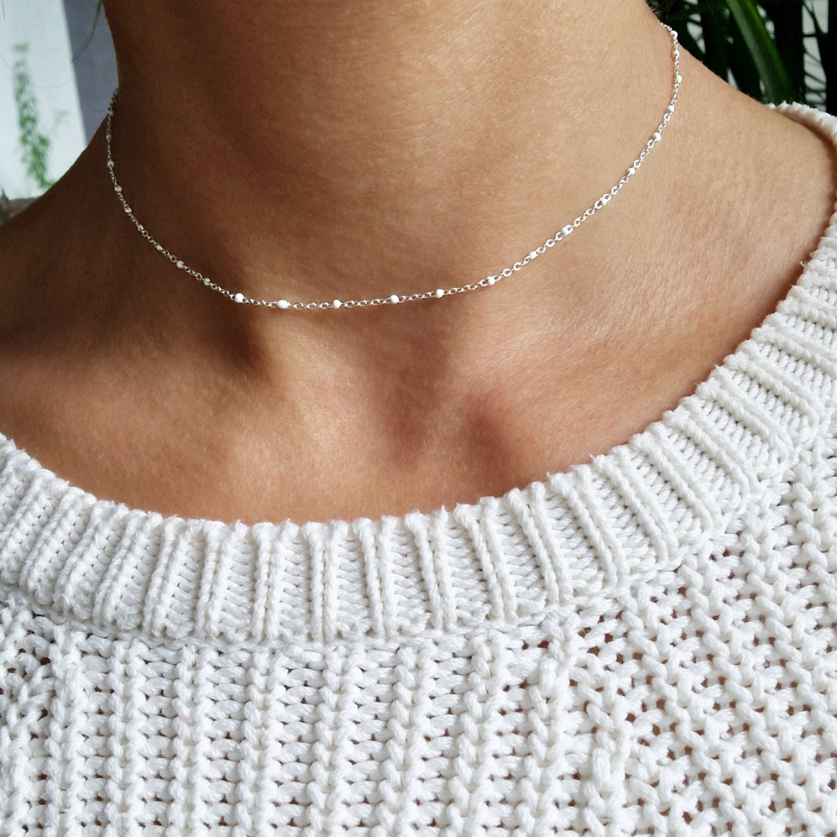 Zarte Layering Silber-Halskette mit weißen Emaille-Kugeln aus einer facettierten Ankerkette am Hals des Models in seitlicher Nahaufnahme