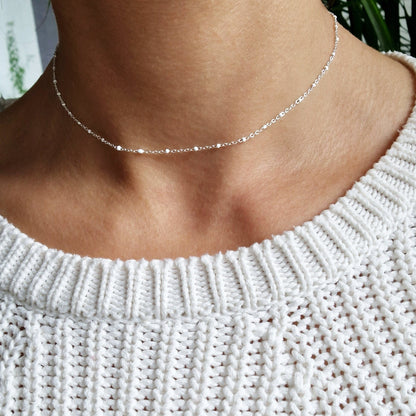 Zarte Layering Silber-Halskette mit weißen Emaille-Kugeln aus einer facettierten Ankerkette am Hals des Models in seitlicher Nahaufnahme