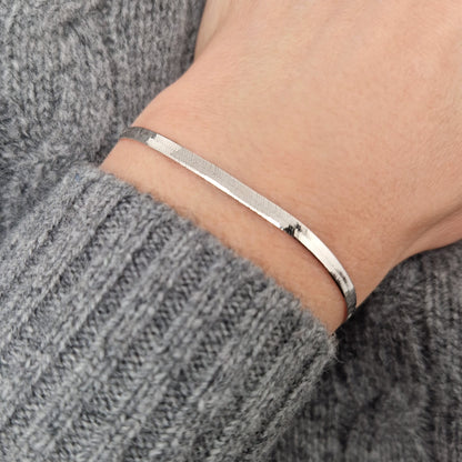 flaches glänzendes Schlangenarmband aus massivem Sterling Silber am Handgelenk des Models.