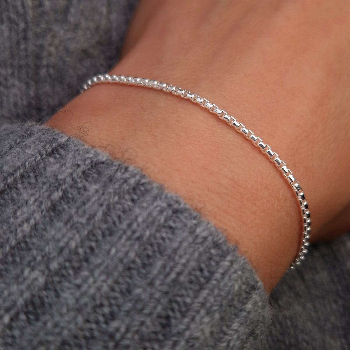 Breites abgerundetes Venezianer Armband aus 925 Sterling Silber am Handgelenk des Models in seitlicher Nahaufnahme mit dunkelgrauem Pulli