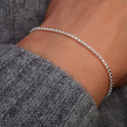 Breites abgerundetes Venezianer Armband aus 925 Sterling Silber am Handgelenk des Models in seitlicher Nahaufnahme mit dunkelgrauem Pulli
