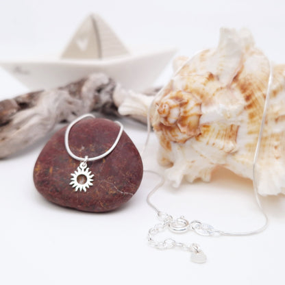 Zarte, runde Schlangenkette mit Mini-Sonne aus massivem 925 Sterling Silber. Die  Sonne ist  aus flachem Silber mit runder Öffnung in der Mitte und geschwungenen verschieden langen Sonnen Strahlen.