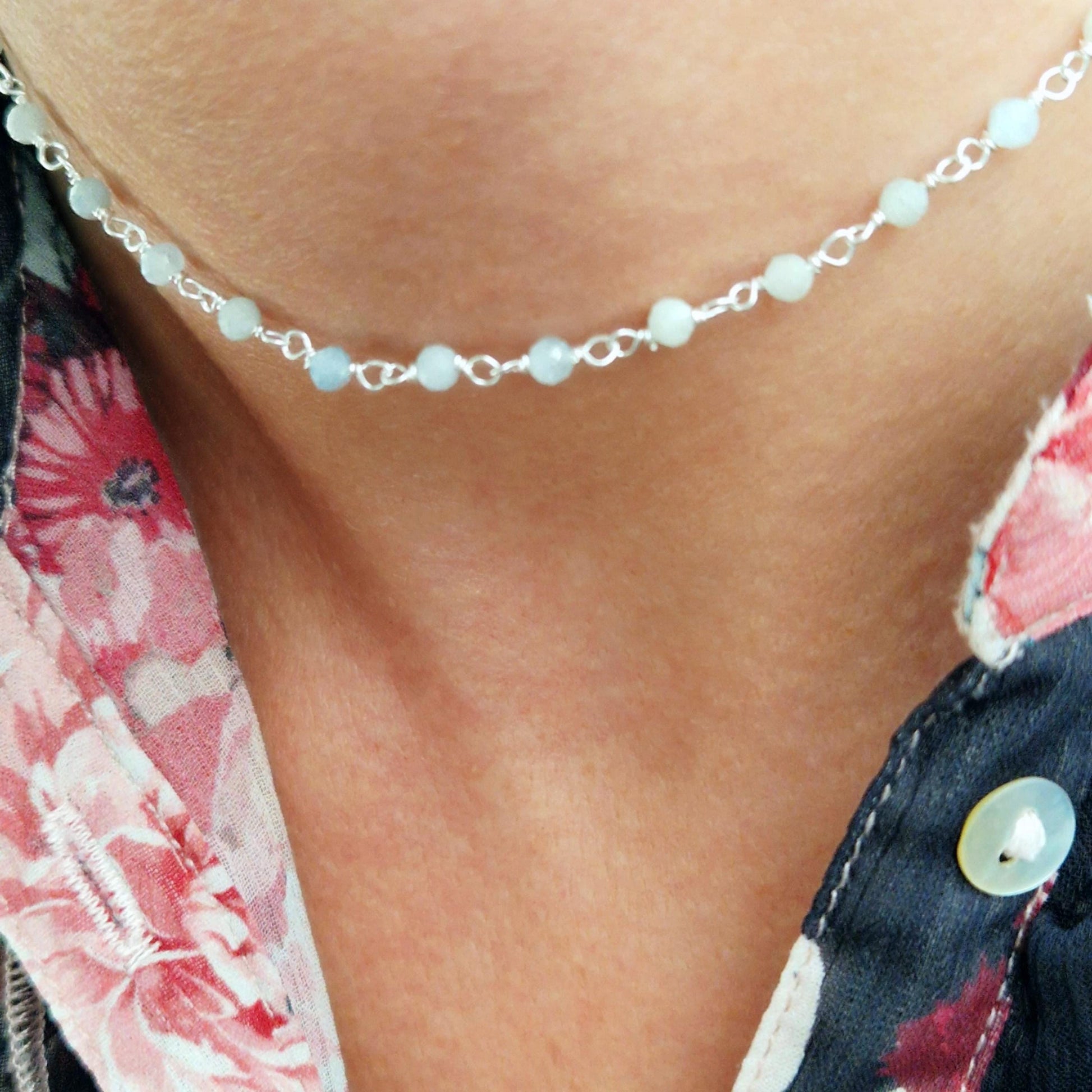zarte Silber halskette mit pastell hellblau facettierten Aquamarin  Perlen aus Naturstein am Has des Models in seitlicher Nahaufnahme mit foraler Bluse