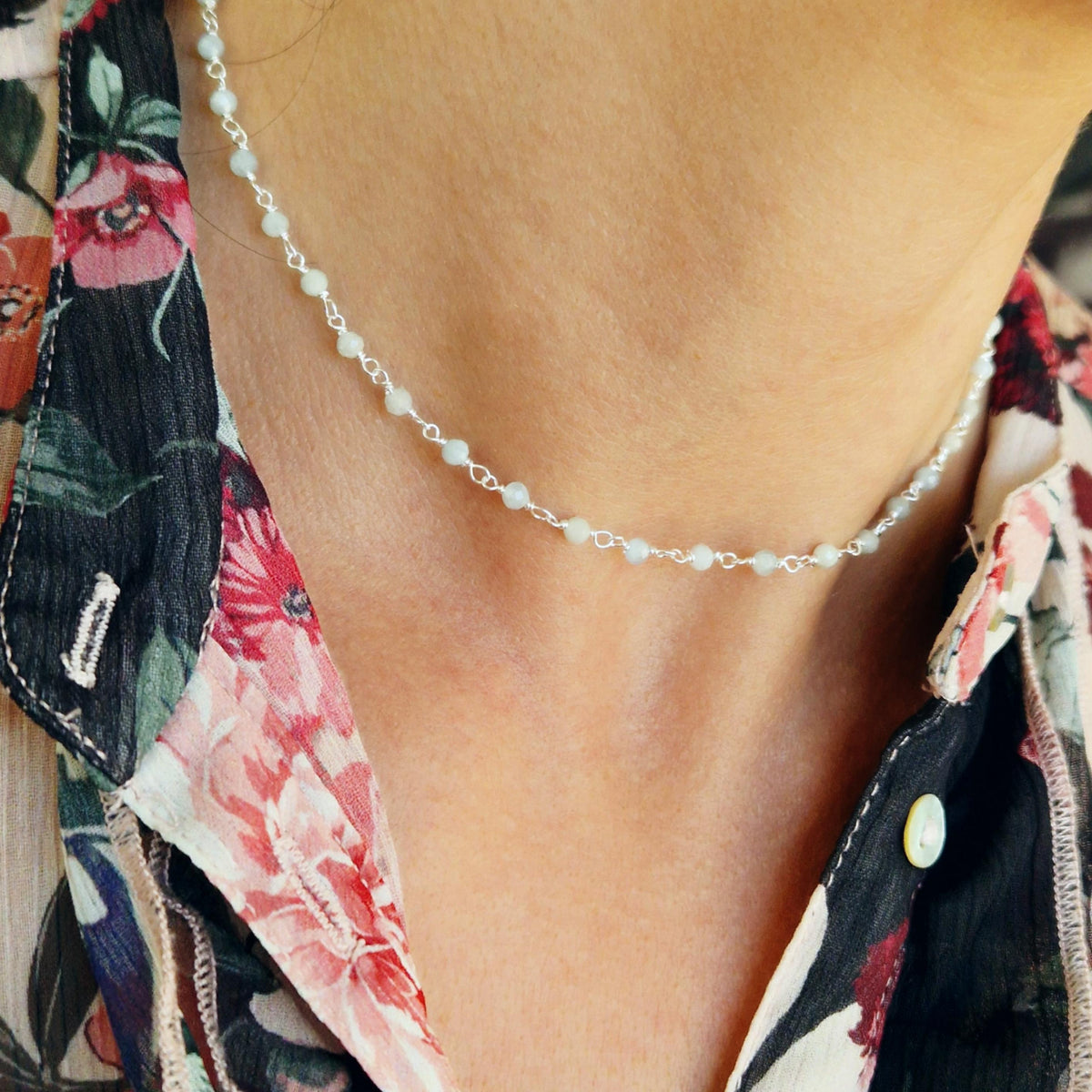 Zarte Halskette aus massivem 925 Sterling Silber mit facettierten Perlen aus grau-blauem Aquamarin am Hals des Models in Nahaufnahme