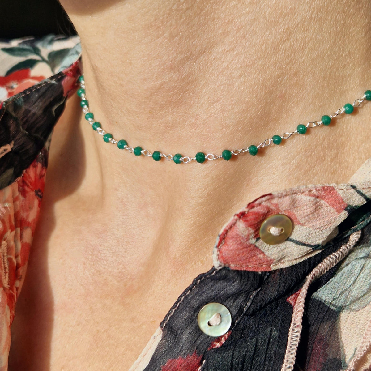 zarte Silber halskette mit 
grünen facettierten  Jade Perlen aus Naturstein am Hals des Models in seitlicher Nahaufnahme mit floraler Bluse