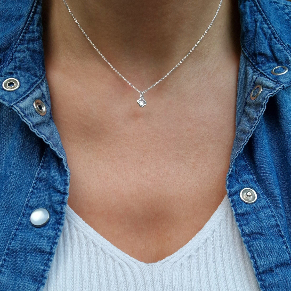 Zarte Silberkette mit zarter kleiner Kristallblume am Hals des Models in frontaler Ansicht mit Jeansjacke und weißem Top