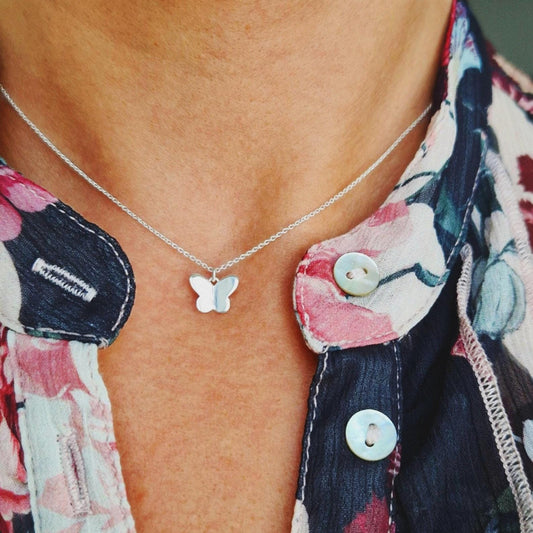 Filigrane Halskette aus massivem 925 Sterling Silber mit kleinem, zartem Schmetterlingsanhänger aus Silber am Hals des Models.