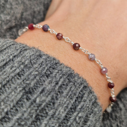 zartes Silber Armband mit grau roten facettierten Turmalin  Perlen aus Naturstein am Handgelenk des Models in seitlicher Nahaufnahme