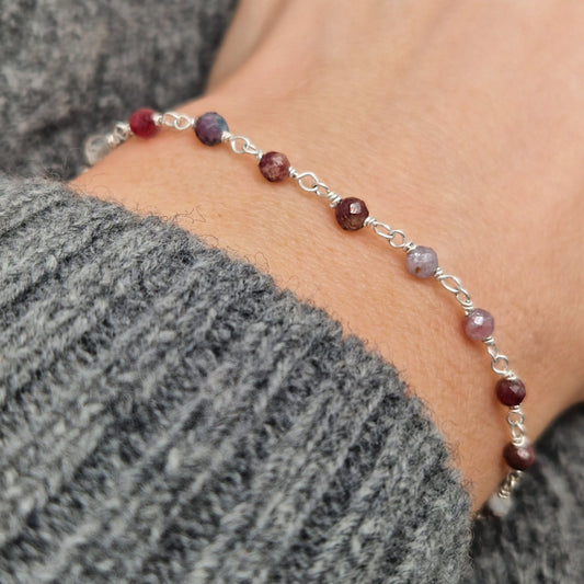 zartes Silber Armband mit grau roten facettierten Turmalin  Perlen aus Naturstein am Handgelenk des Models in seitlicher Nahaufnahme
