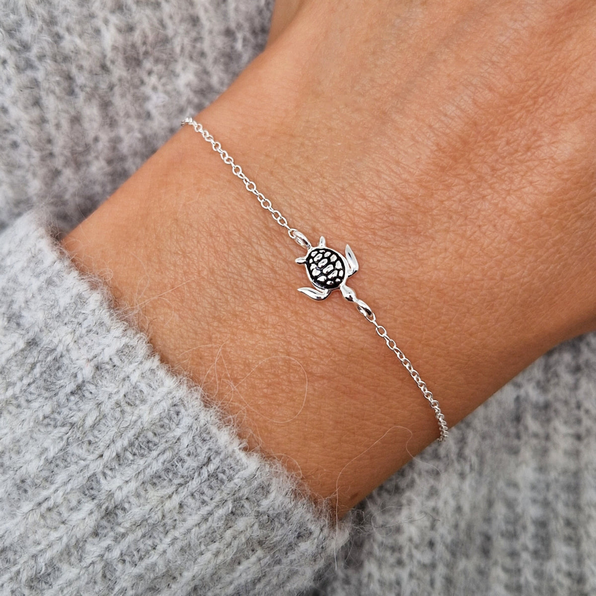 Zartes Silberarmband mit Schildkrötenanhänger aus massivem925 Sterling Silber am Handgelenk des Models in Nahaufnahme
